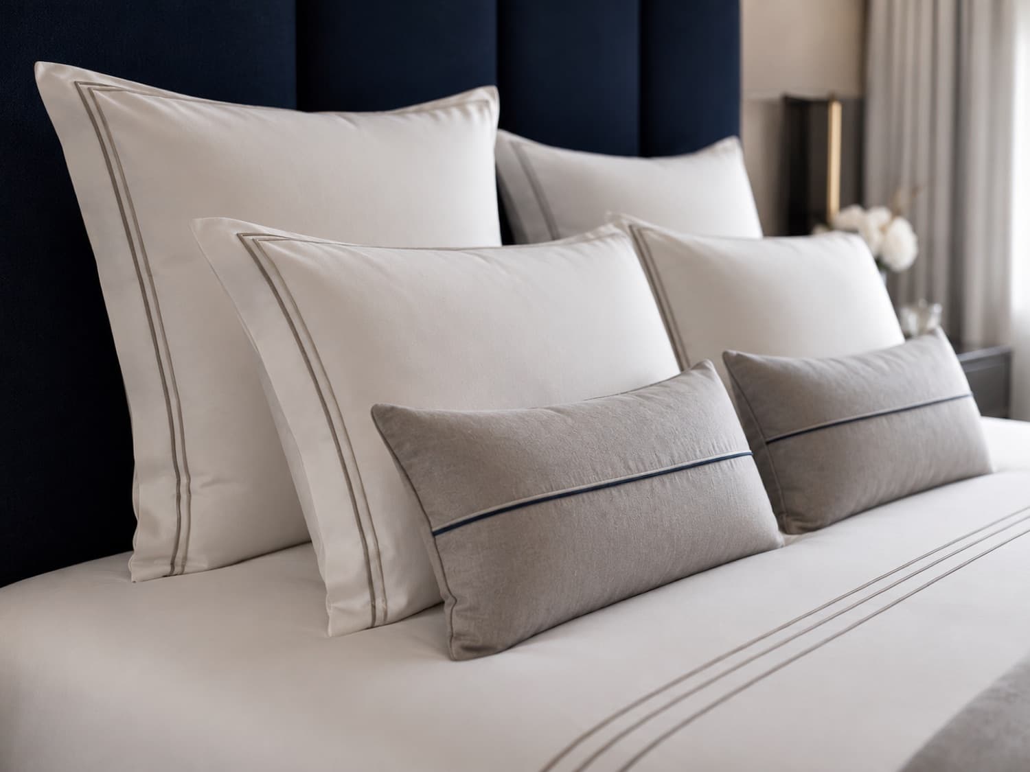 A hotel bed dressed with pillows, cushions, and fine linen