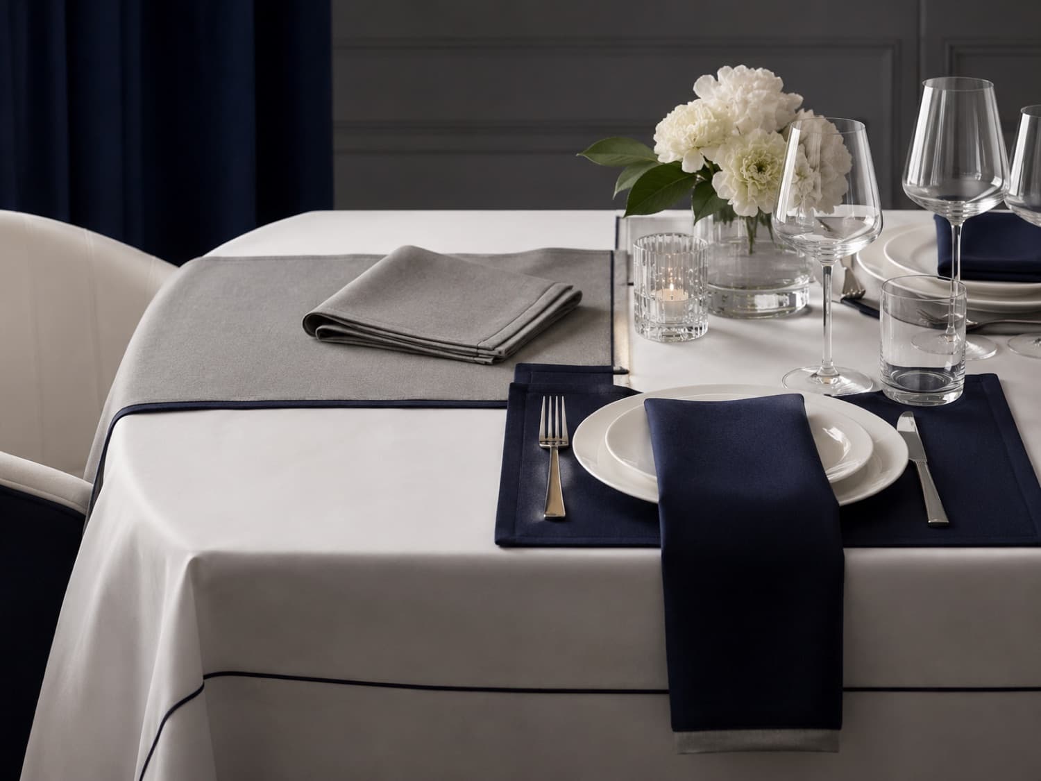 A dining table dressed with tablecloth, napkins, and placemats